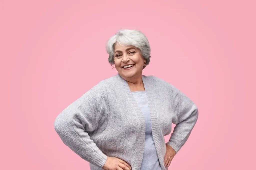 Cheerful senior female looking at camera with pink background