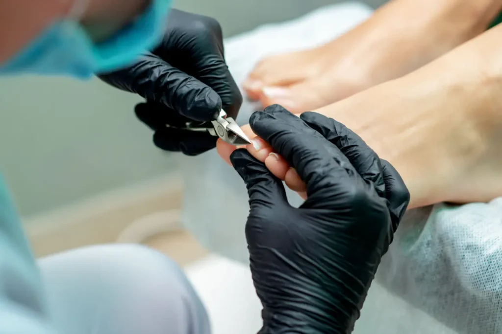 nurse at a toenail cutting service cuts toenails of woman during pedicure procedure.
