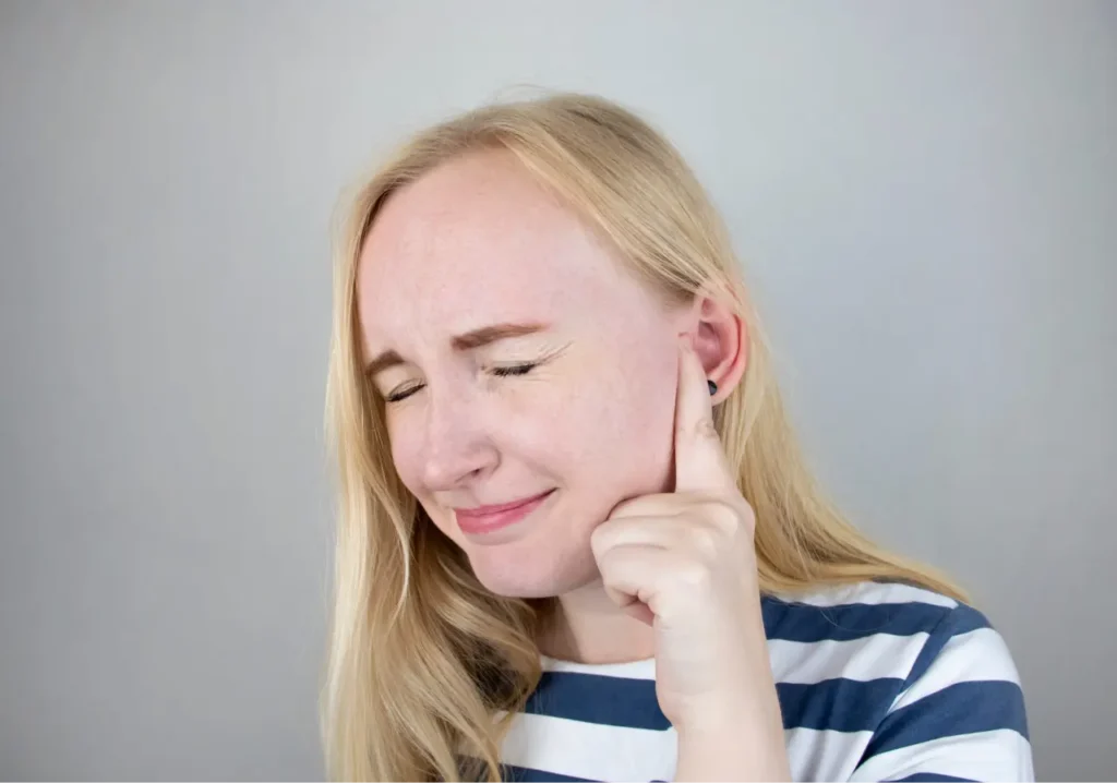 A woman suffers from pain in the ear.