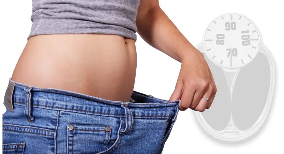 woman pulling trousers open to show how much weight loss injections have helped.